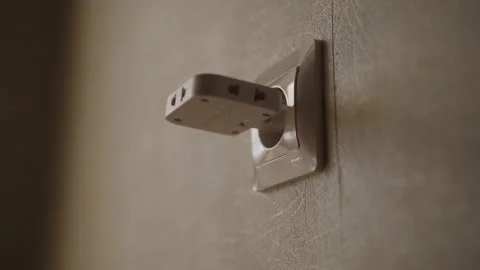 Close-up hand of unrecognizable person inserts white electrical plug into wall 動画素材 342769188
