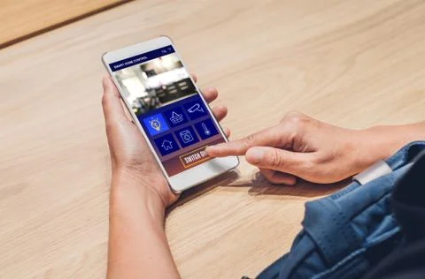 Close up hand use smart home control app on mobile phone switch on light.Auto Stock Photos