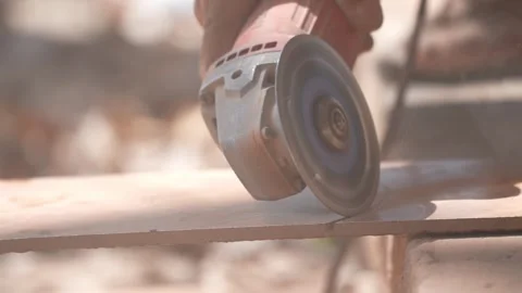 Close-up of a hand using an angle grinder to cut metal, sparks blurred in warm l Stock-Footage 333330472