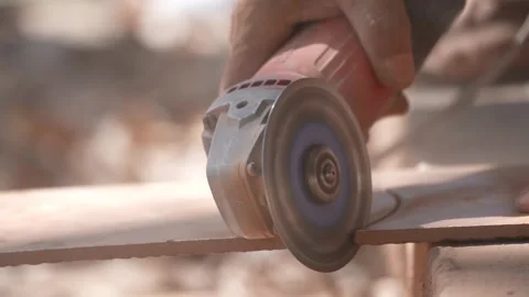 Close-up of a hand using an angle grinder to cut metal, sparks blurred in warm l Stock-Footage 333330474
