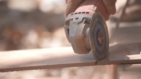 Close-up of a hand using an angle grinder to cut metal, sparks blurred in warm l Stock-Footage 333330485