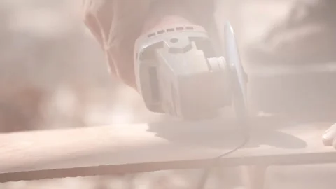 Close-up of a hand using an angle grinder to cut metal, sparks blurred in warm l Stock-Footage 333330489