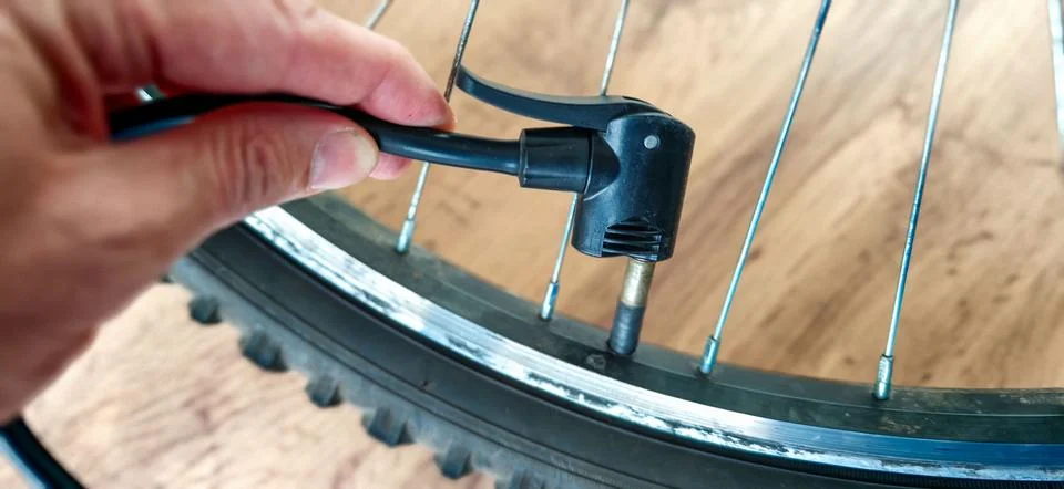 Close-up of a hand using a bicycle pump nozzle to inflate a tire valve, showc Stock Photos