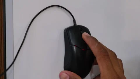 Close-up of a Hand Using a Black Wired Optical Mouse on a White Surface Stock Footage 330572881