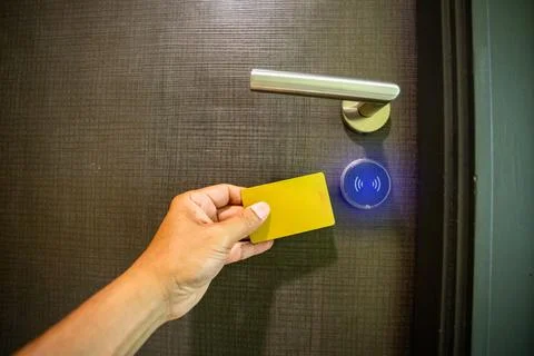 Close-up of a hand using a card to unlock a hotel door with a glowing blue .. Foto stock