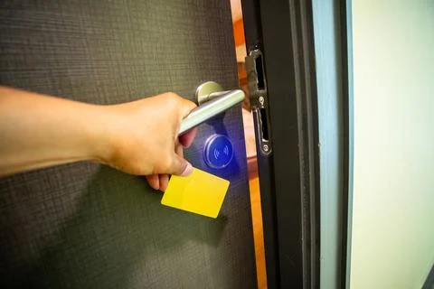 Close-up of a hand using a card to unlock a hotel door with a glowing blue .. Stock Photos