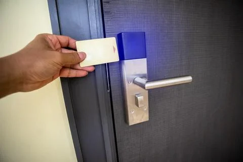 Close-up of a hand using a card to unlock a hotel door with a glowing blue .. Stock Photos