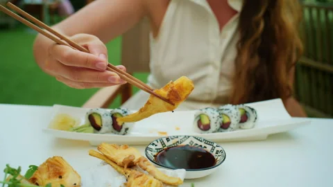 Close-up of a hand using chopsticks to dip artichoke tempura in soy sauce Stock Footage 344794035