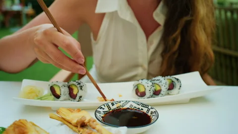 Close-up of a hand using chopsticks to dip pickled ginger in soy sauce Stock Footage 344794045