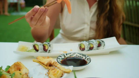 Close-up of a hand using chopsticks to dip salmon sashimi in soy sauce Stock Footage 344794260