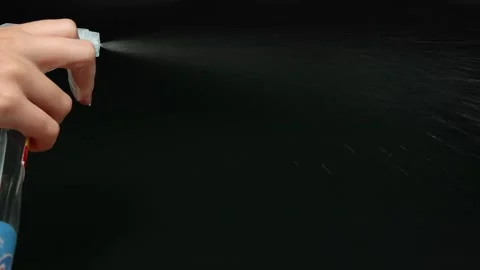 Close up hand using cleaning spray bottle on black background in slow motion. Stock Footage 332581477