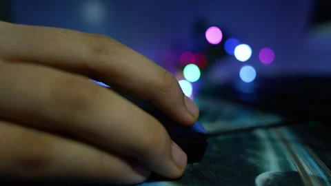 Close-up of a hand using a computer mouse on a desk with colorful blurred l.. 動画素材 337899229