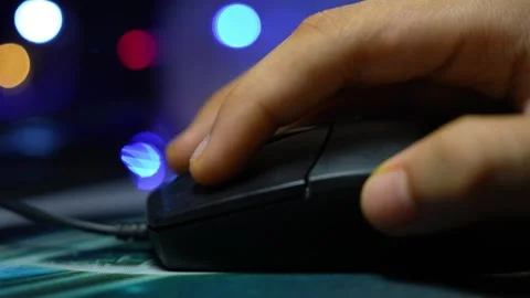 Close-up of a hand using a computer mouse on a desk with colorful blurred l.. Stock Footage 337899245