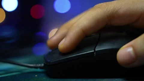 Close up of a hand using a computer mouse with blurred colorful lights in t.. Видео 337899271