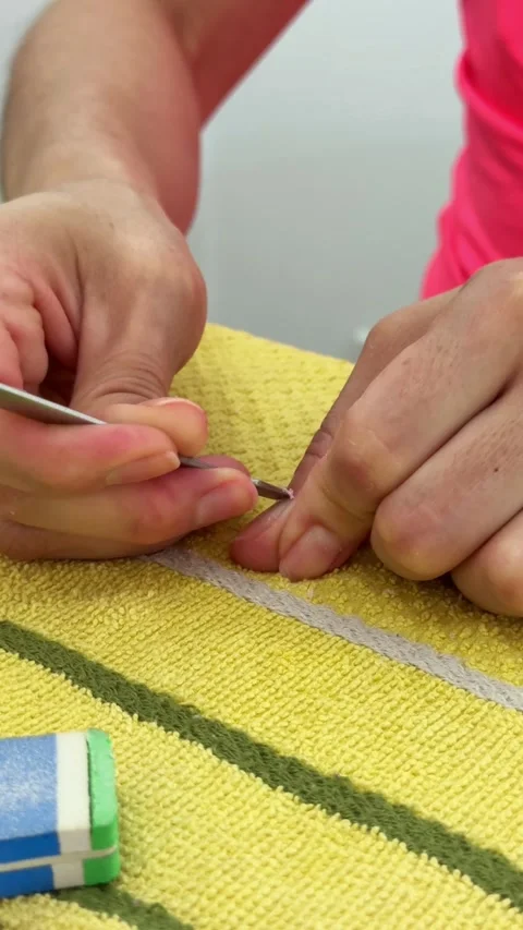 Close-up hand using cuticle pusher on fingernail during manicure Video stock 325656811