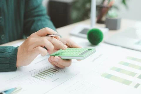 Close-up of hand using green calculator on financial charts with eco earth .. Foto stock