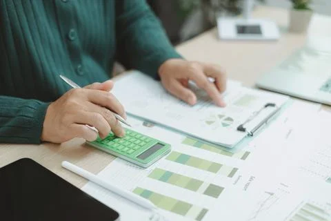 Close-up of hand using green calculator on financial charts with eco earth .. Stock Photos