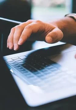 Close-up of hand using a laptop computer with a blurred background Stock Photos