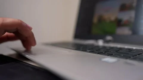 Close-up of a hand using a laptop touchpad, blurred screen in background Stock Footage 317131697