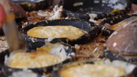 Close up of a hand using a metal spatula to shape small round batter cakes in bl Stock Footage 339279924
