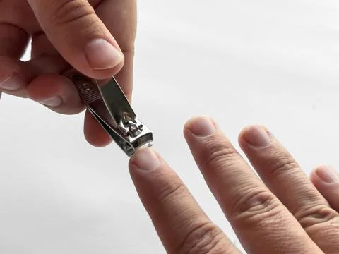 Close up of hand using nail clipper for personal grooming on white background Stock Photos