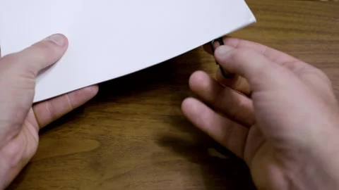 Close up of a hand using a paper clip connecting to a stack of paper. A4 size Stock Footage 336719654