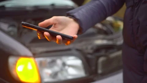 Close-up of hand using phone on background of car with flashing alarm Stock Footage 144077186