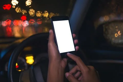 Close-up hand using phone inside car on night in city Foto stock