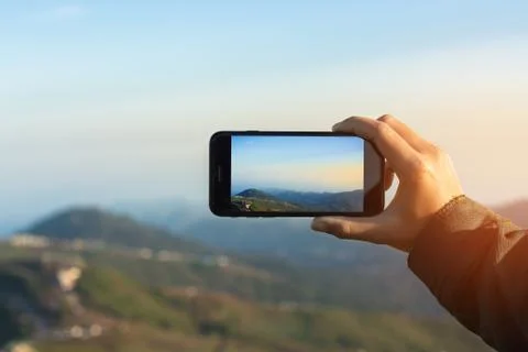 Close-up hand using phone mobile taking photo mountain view on morning Stock Photos