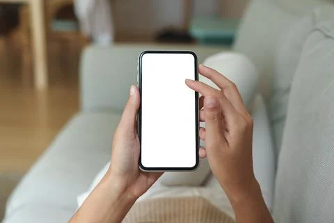 Close-up hand using phone showing white screen in living room Stock Photos