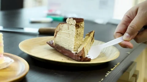 Close up hand using plastic fork cutting slice of chocolate mille crepe cak.. Stock Footage 333431749