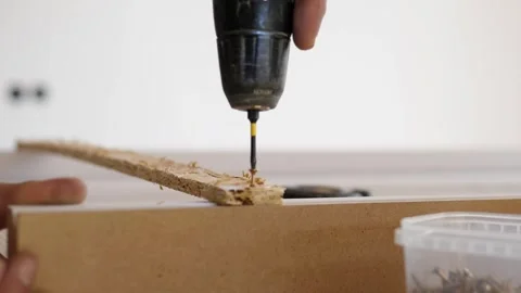 Close up hand using power drill to make precise hole in cardboard edge during Stock Footage 344871760