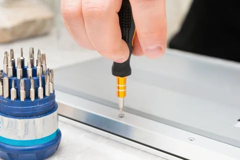 Close-up of a hand using a precision screwdriver to tighten a screw on a me.. Foto stock