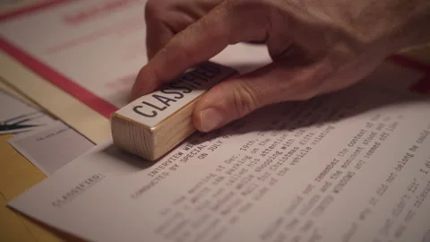 Close up on hand using red rubber stamp to mark document report as classified Stock Footage 311059330
