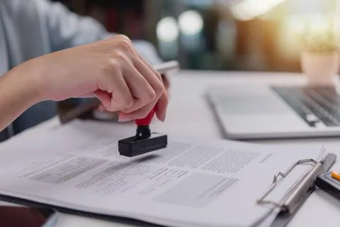 Close-up of hand using a red stamp on a legal document, indicating confirma.. 스톡 사진