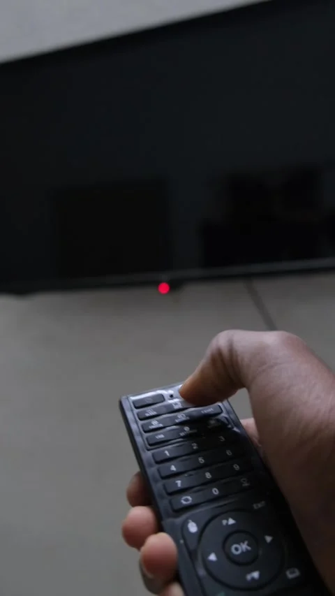 Close up of a hand using a remote control to turn on a TV Видео 331004485