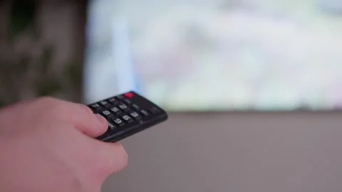 Close Up of Hand Using Remote Control with Blurred TV Screen Stock-Footage 333608356