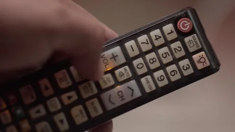 Close Up of Hand Using Remote Control Device Pressing Buttons Indoors Gently Stock Footage 338394394