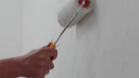 Close-up of a hand using a roller brush to paint a textured white wall, hig.. Stock Footage 309550705