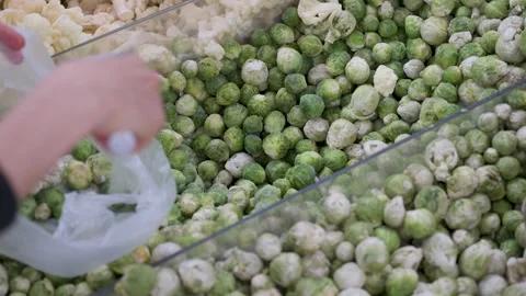 Close-up of a hand using scoop to select frozen Brussels Sprouts from freez.. Video stock 308363930