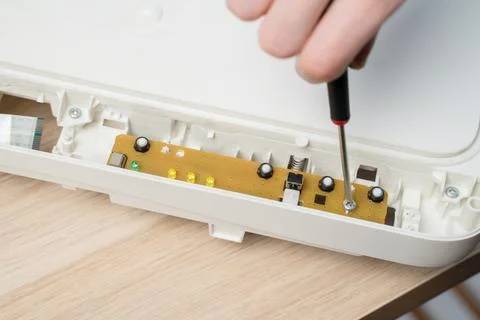 Close-up of a hand using a screwdriver to remove a screw from an exposed circ Stock Photos