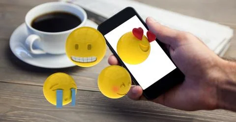 Close-up of hand using smart phone while emojis flying over table Stock Photos