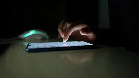 Close-up of a hand using a smartphone in a dark room, with a glowing mouse .. Stock Footage 317736838