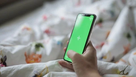 Close up of hand using a smartphone with green screen display indoors. The girl  Stock Footage 96914416