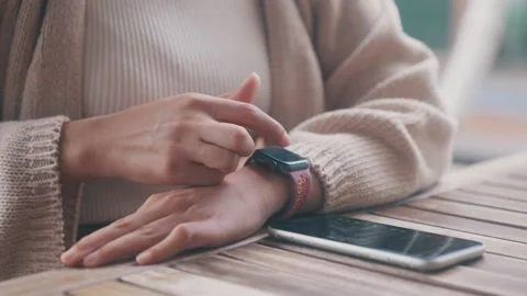 Close-up hand using smartwatch and phone on table Stock Footage 201614275