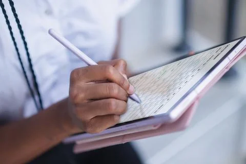 Close up of hand using stylus on tablet with digital planner interface. Sch.. Fotos Stock