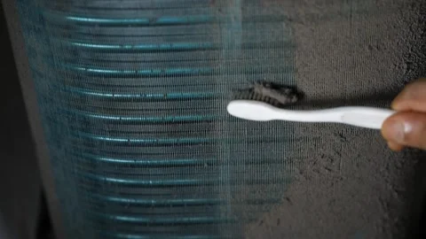 Close-up of a hand using a toothbrush to clean dust from an air conditioner.. Stock-Footage 338319343