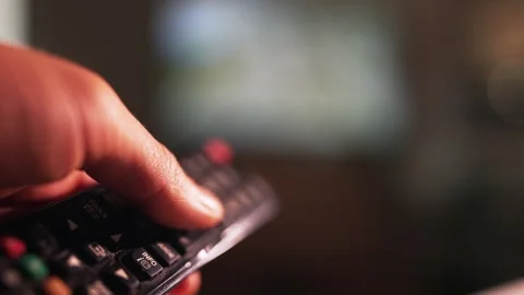 Close-Up of Hand Using a TV Remote Control Stockbeeldmateriaal 337737242