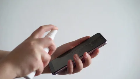 Close-up of hand using wet wipe and sanitizer spray to clean cell phone screen. Stock Footage 128315209