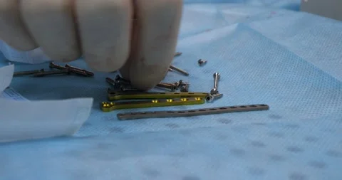 Close-up. The hand of a veterinary surgeon takes a screw from the table in the Stock Footage 239859348